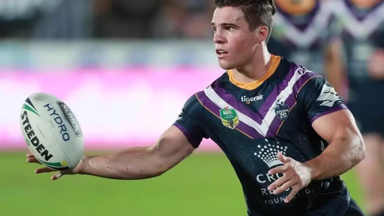 Brodie Croft carrying the ball in a purple Melbourne Storm playing kit